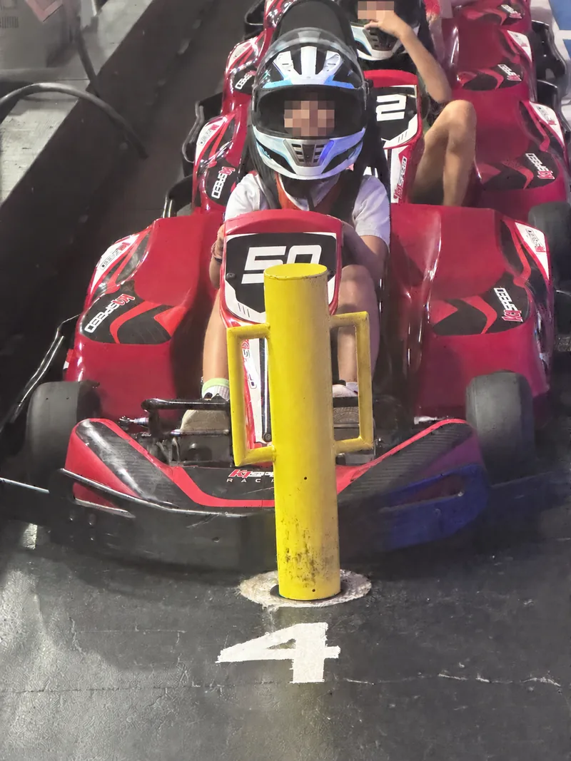 A child racing an indoor go-kart at K1 Speed Austin; visible children’s faces are obscured for privacy