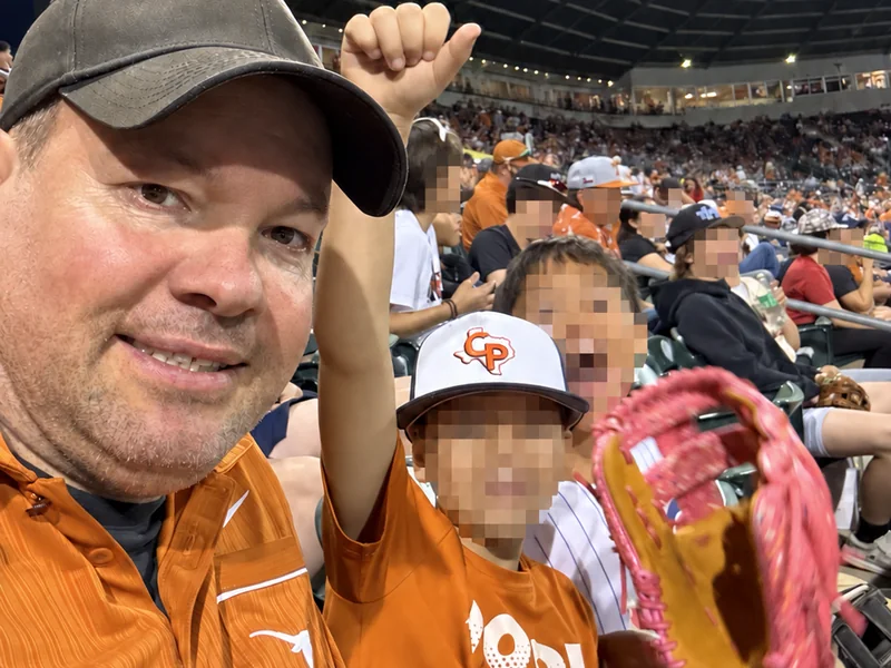 Mark with two children at a Texas baseball game; the children and young spectators’ faces are obscured for privacy